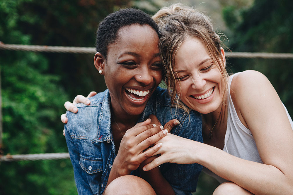 Two friends with their arms around each other, laughing