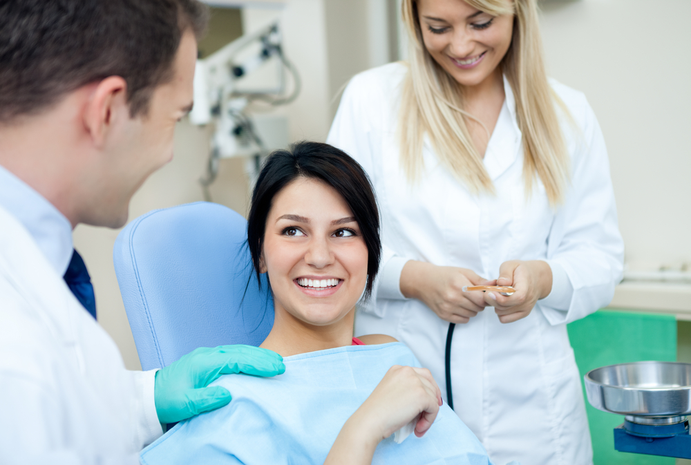 A patient sitting in the dental chai smiling at dentist