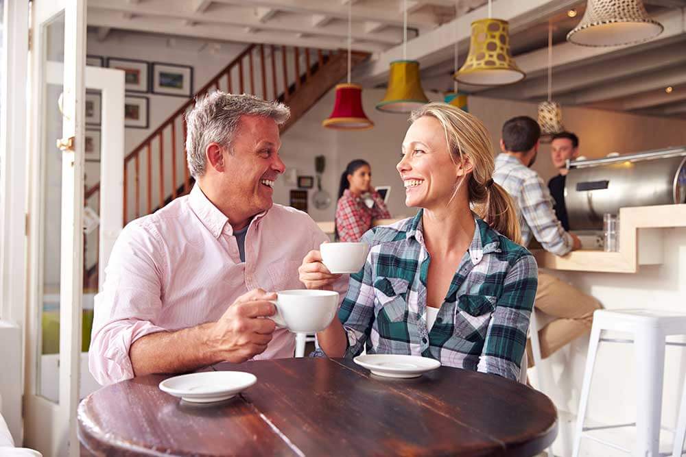 A man and woman laughing while on a coffee date