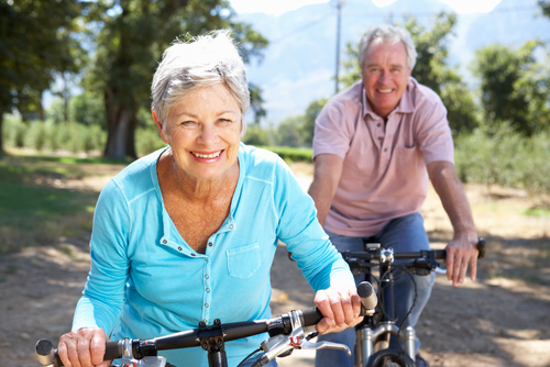 A man and woman smiling and riding bikes on a trail