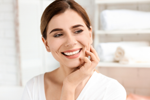 A middle aged resting her chin on her hand and smiling