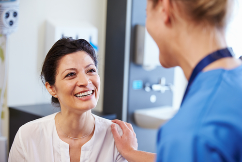 A doctor with her hand on a smiling patient's shoulder